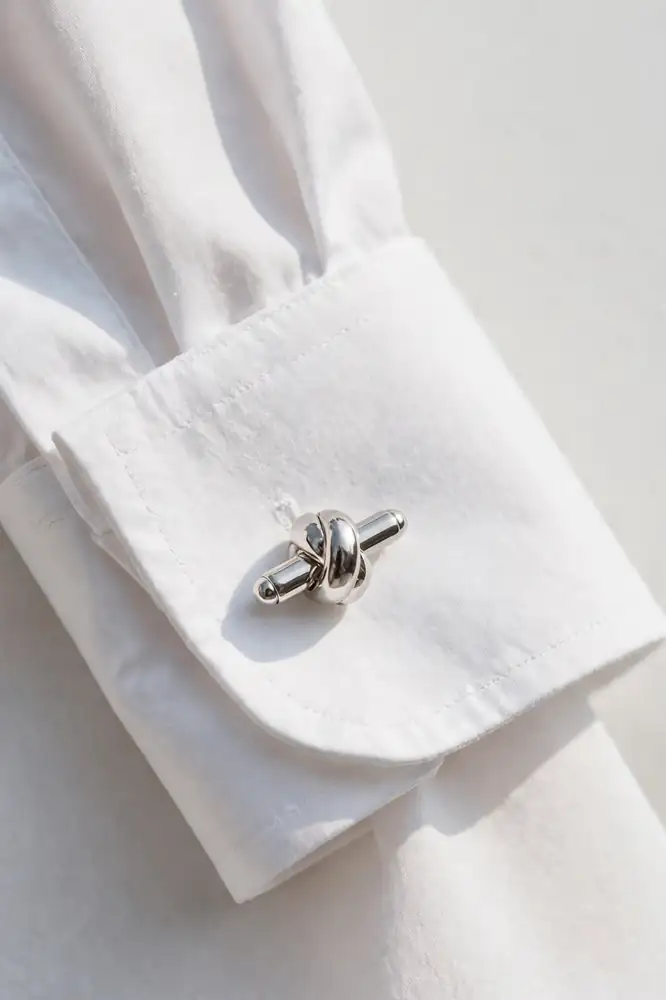 Silver cufflinks on a white French cuff shirt close-up