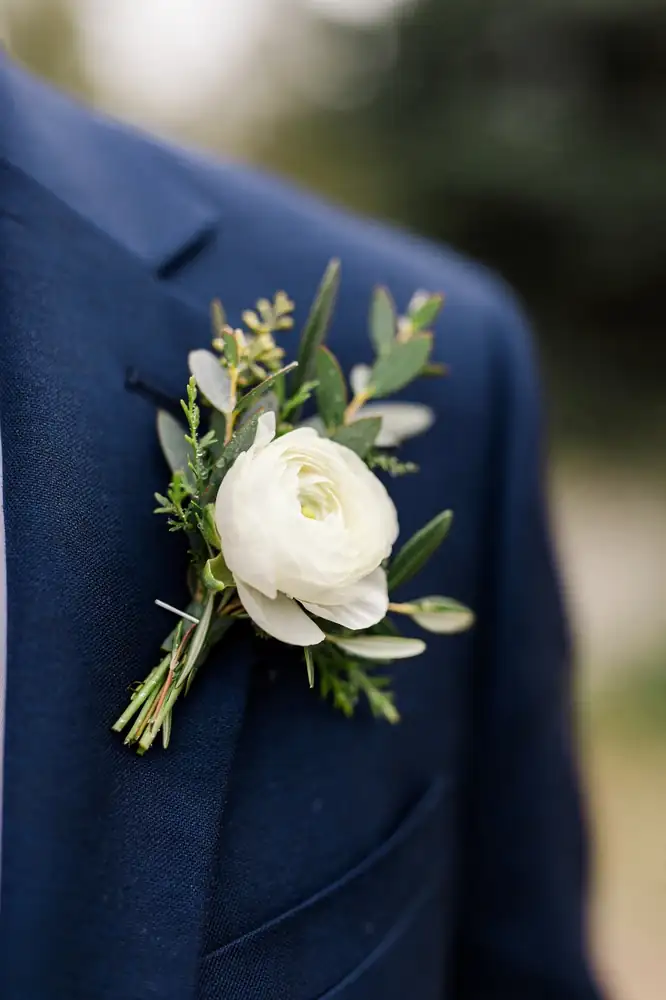 White ranunculus boutonniere pinned to a navy suit lapel