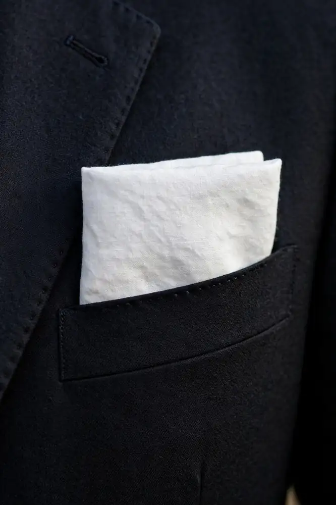 White linen pocket square in a dark suit breast pocket
