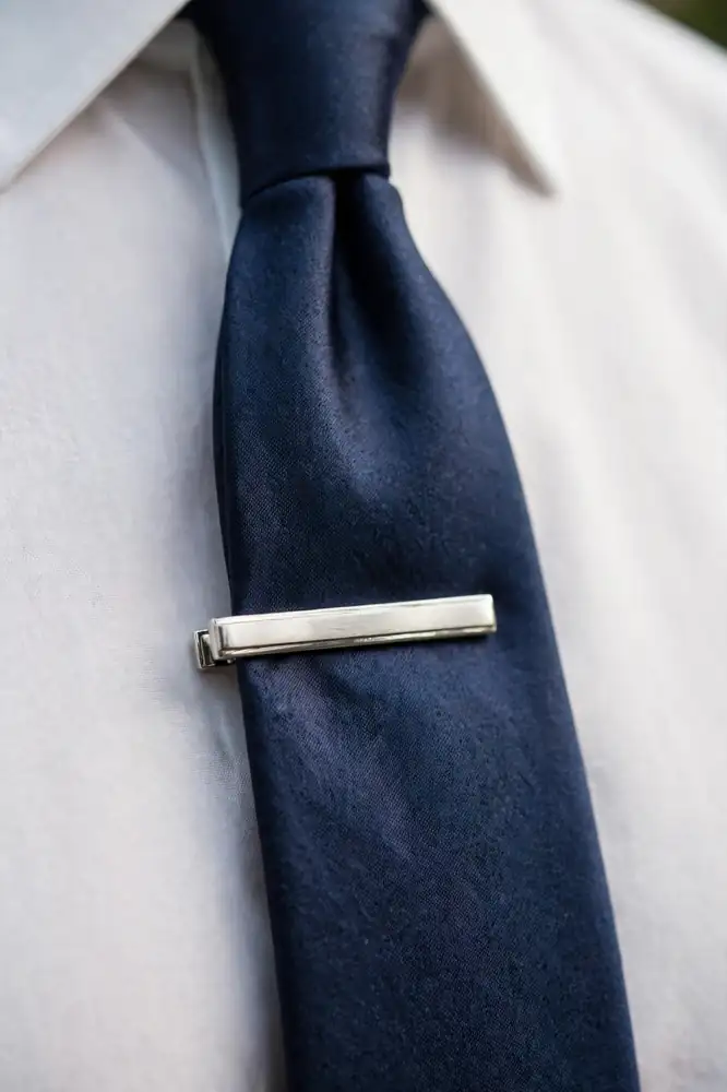 Silver tie bar clipped on a navy silk tie close-up
