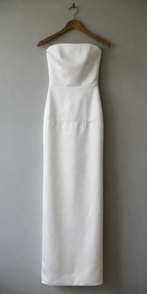 Strapless white satin column wedding dress with drop waist on a hanger
