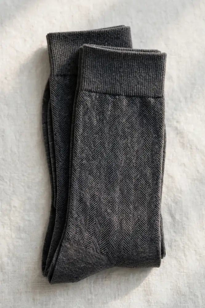 Folded pair of dark grey patterned dress socks