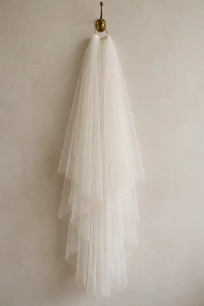 Waltz-length bridal veil with tiny pearls hanging from a brass hook